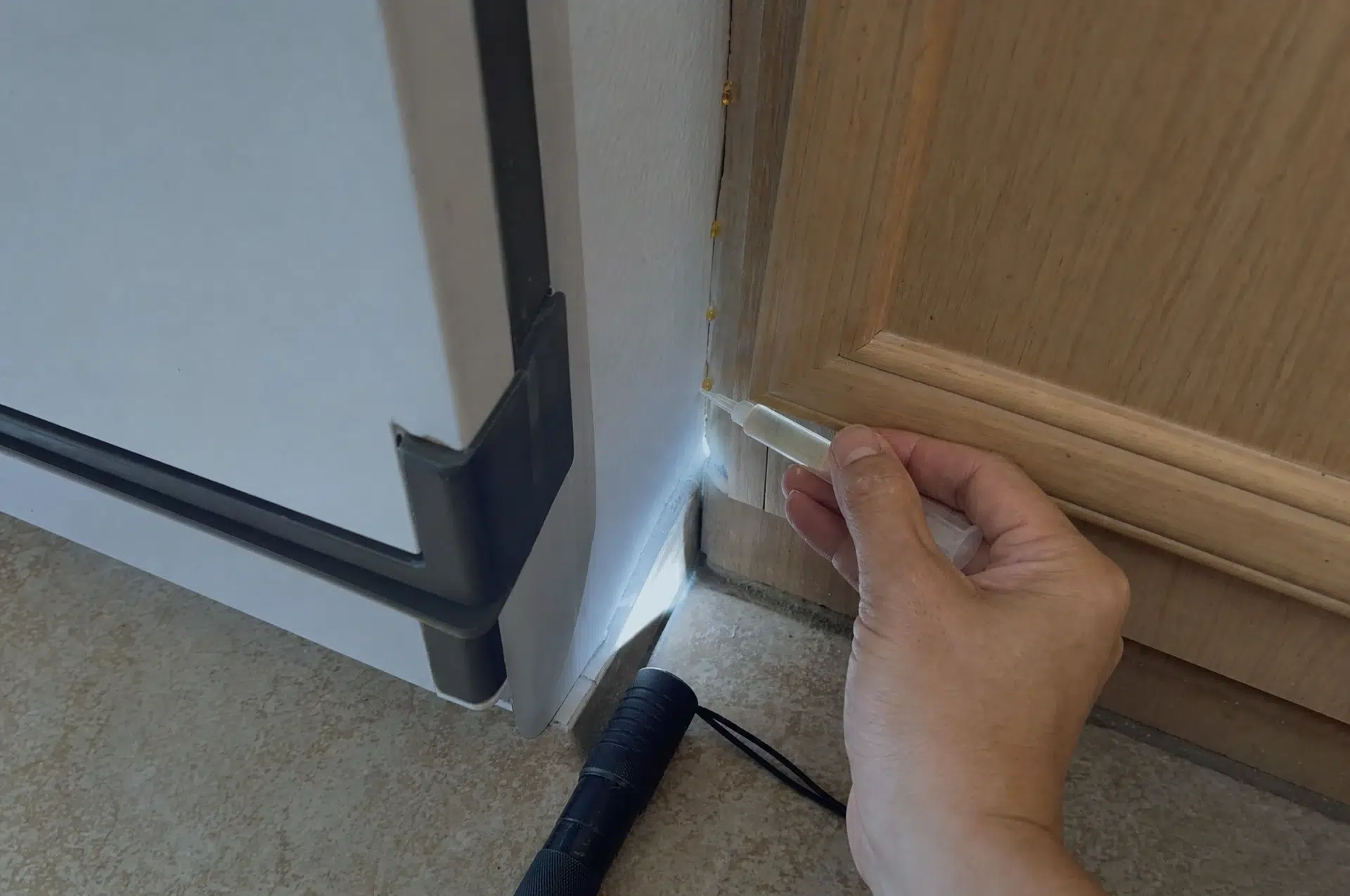Schabengel anwenden: Gel-Tropfen in der Ritze hinter dem Kühlschrank
