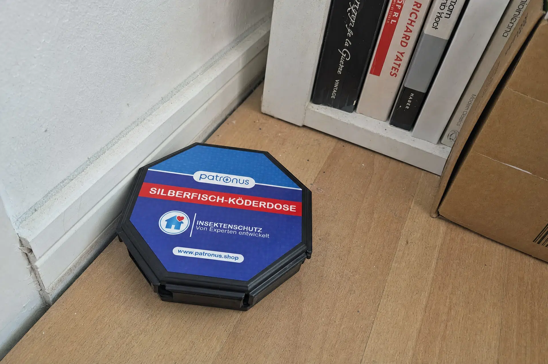 Papierfische bekämpfen mit der Köderdose an der Sockelleiste neben dem Bücherregal